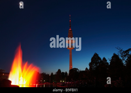 Beleuchtete Brunnen in der Nähe Fernmeldeturm vor düsteren Himmel, Hamburg, Deutschland Stockfoto