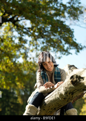 Porträt von Reife Frau auf umgestürzten Baum lächelnd Stockfoto