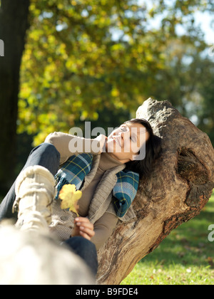 Reife Frau ruht auf umgestürzten Baum und lächelnd Stockfoto
