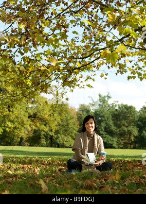 Porträt von Reife Frau Buch hält und lächelnd in park Stockfoto