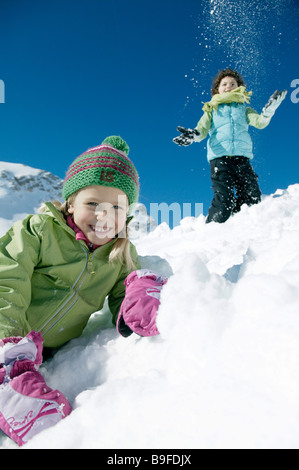 Porträt von Mädchen lächelnd auf schneebedeckter Landschaft mit jungen im Hintergrund Stockfoto