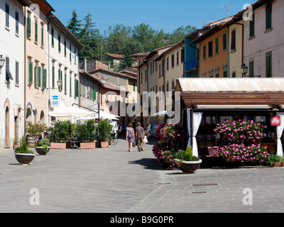 Der Hauptplatz im Dorf Borgo di Gaiole in Italien mit Cafés und Touristen, die bei strahlendem Sonnenschein Wandern Stockfoto