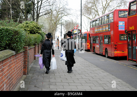 Strreet Szene zwei junge orthodoxe jüdische Männer mit shopping während des Festivals von Purim, Stanford Hill London Stockfoto