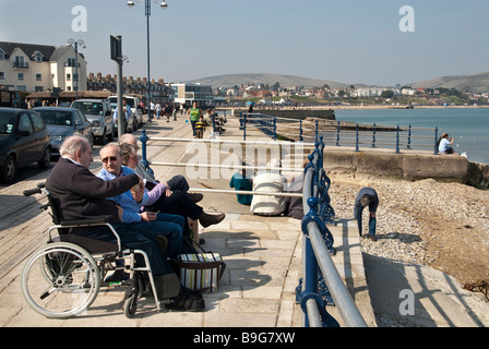 Auf der Promenade am Swanage einschließlich Mann im Rollstuhl sitzen Stockfoto