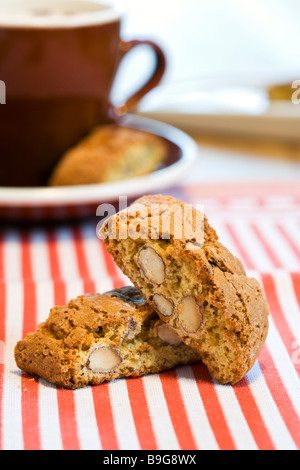 zwei italienische Cantuccini Mandel Cookies, Tasse Cappuccino im Hintergrund Stockfoto