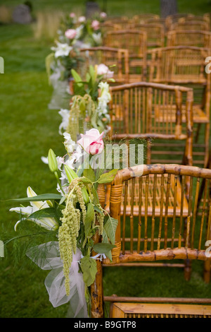 Stuhlreihen an eine Bauernhochzeit mit rosa und grüne Blumen geschmückt Stockfoto