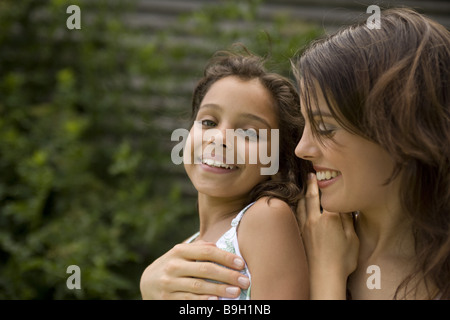 Mutter Tochter umarmt liebevoll lächelnd Porträt vor 10-12 Jahren 11 Jahre 20-30 Jahren 30-40 Jahre außerhalb außen braun Stockfoto