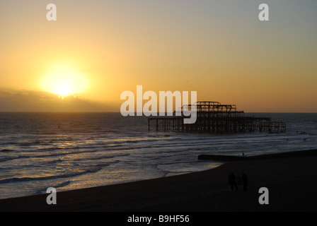 Sonnenuntergang hinter dem zerstörten Pier am Brighton Beach East Sussex England mit Stare Schlafplatz Stockfoto