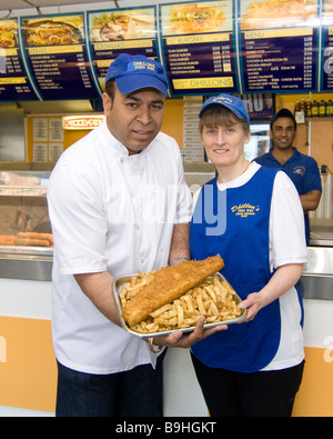 Dillons Fischgeschäft in Prudhoe mit Herrn Dhillon und Mitarbeiter posiert mit Fish &amp; Chips vor Fisch-Fritteuse Stockfoto