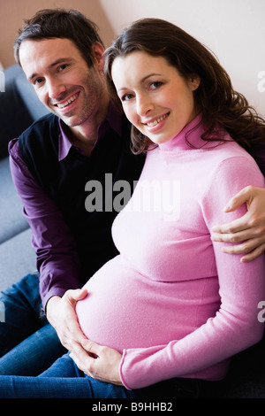 Schwangere Frau und Mann sitzt auf der couch Stockfoto