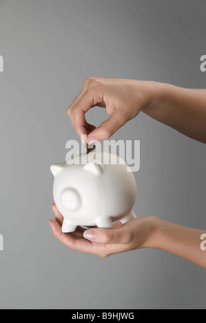 Weibliche Hand Platzierung Münze im Sparschwein Stockfoto