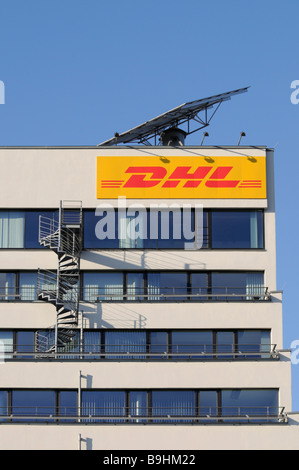 DHL-Logo auf einem Bürogebäude, darüber ein mobiles Solarmodul, angebautem Feuertreppe Stockfoto