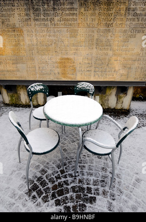 Schnee-bedeckten Tisch und Stühle eines Cafés vor einem Denkmal für die Kriegsopfer Platte, Marbach am Neckar, Baden-Württemberg, Ge Stockfoto