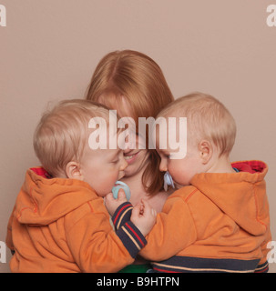 Mutter hält Zwillingssöhne Stockfoto