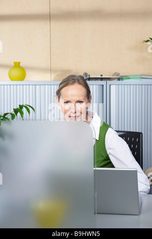 Ältere Frau sitzt am Schreibtisch Stockfoto
