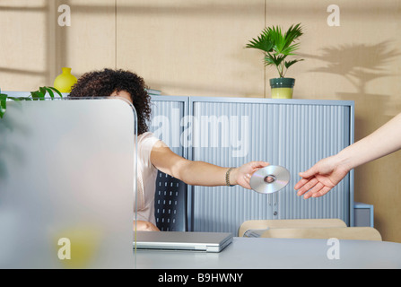 Frau, die Übergabe der DVD von anderen Mitarbeitern Stockfoto