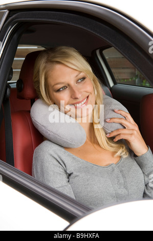 Blonde Frau mit einem Nackenkissen in einem Auto sitzen Stockfoto