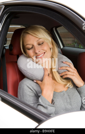 Blonde Frau mit einem Nackenkissen in einem Auto sitzen Stockfoto