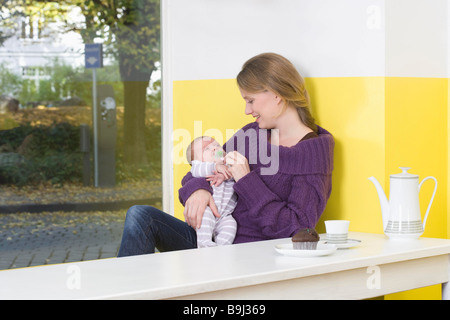 Junge Frau mit Baby auf Tisch Stockfoto