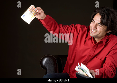 Junger Mann winkt ein 50 Euro-Schein, glücklich über seine volle Brieftasche Stockfoto