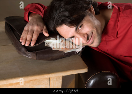 Junge, Content Mann ruht auf seine Tasche voller Geld Stockfoto