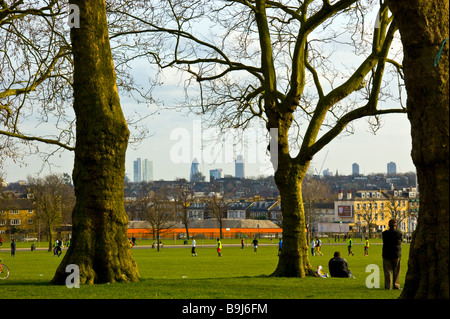 Sonntag Nachmittag im Finsbury Park. Reifen Eichen & Zuschauer bei einem Fußballspiel mit der Londoner Skyline in der Ferne Stockfoto