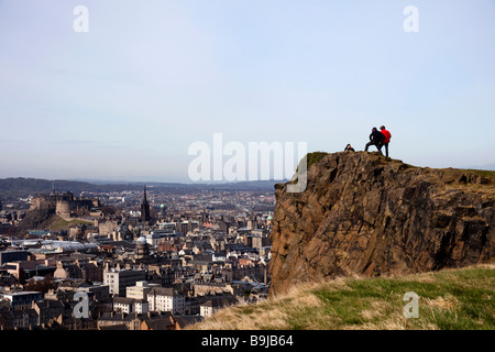 Drei Männer auf der Oberseite Salisbury Crags Holyrood Park, Edinburgh, Scotland, UK, Europa, mit der Stadt im Hintergrund Stockfoto