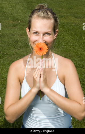 Frau junge blonde Gerbera-Blüte lächelnden Portrait-Serie Menschen Top String Top Blume Gerbera Sommerblume Entspannung Stockfoto