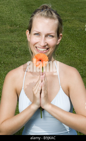 Frau junge blonde Gerbera-Blüte lächelnden Portrait-Serie Menschen Top String Top Blume Gerbera Sommerblume Entspannung Stockfoto