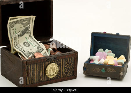 Zwei kleine Schatztruhen voller Geld, ein weiteres mit herzförmigen Bonbons Stockfoto