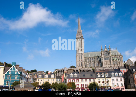 Cobh Hafen und Geschäften mit St. Colman Kathedrale im Hintergrund an einem sonnigen Tag, Irland Stockfoto