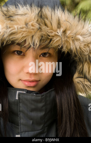 Eine junge asiatisch-amerikanische Frau trug eine schwarze Jacke mit Pelz gefütterten Kapuze. Stockfoto