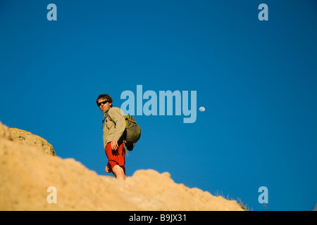 Ein Portrait eines jungen Mannes, der auf einem Felsen mit einem strahlend blauen Himmel hinter in Channel Islands Nationalpark, Kalifornien. Stockfoto