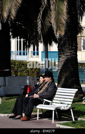 Schönes Frankreich, Straßenszene älteres Paar, Senioren sitzen auf einer öffentlichen Bank auf dem Bürgersteig, Promenade des anglais france, sitzen unter einem Baum Stockfoto