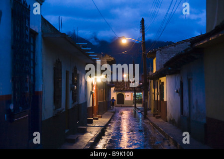Eine Frau geht allein auf ein nass und leere Straße in der Nacht in San Cristobal de Las Casas, Chiapas, Mexiko. Stockfoto