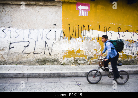 Eine junge Fahrräder vorbei EZLN Graffiti in einer Straße von San Cristobal de Las Casas, Chiapas, Mexiko. Stockfoto