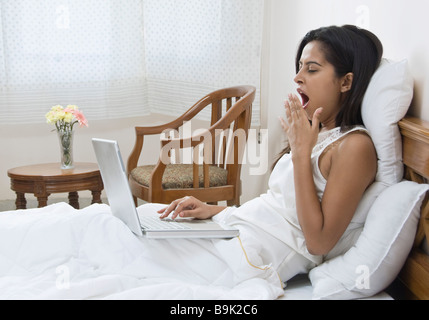 Frau mit einem Laptop auf dem Bett Stockfoto