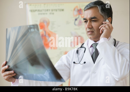 Doktor Untersuchung eine Röntgenaufnahme und telefonieren mit einem Handy Stockfoto
