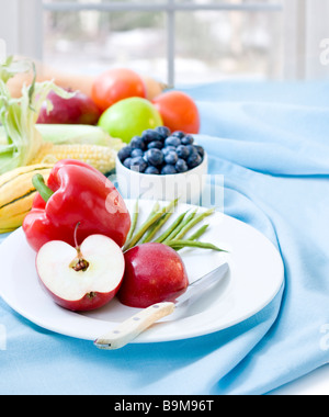 Nahaufnahme von geschnittenen Äpfeln und Paprika in Plage mit frischem Obst und Gemüse im Hintergrund Stockfoto