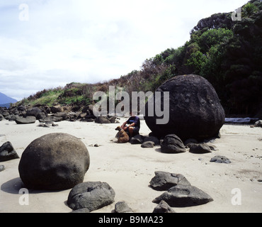 Mensch und Hund sitzt neben Hokianga Boulder Konkretion, Nordinsel, Neuseeland. Stockfoto