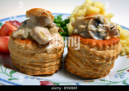 Ein Abendessen mit Huhn und Pilzen gefüllt Vol-au-vents mit Kartoffeln, Erbsen und Tomaten, extreme Nahaufnahme Stockfoto