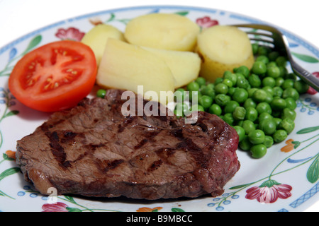 Eine Mahlzeit aus gegrilltem Rumpsteak, Erbsen, Kartoffeln und Tomaten. Stockfoto