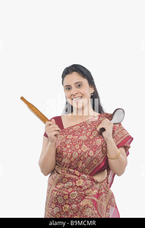 Porträt einer Frau halten Küchenutensilien und lächelnd Stockfoto