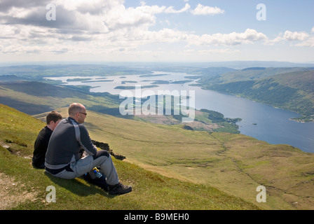 Wanderer mit Blick auf die atemberaubende Aussicht vom Gipfel des Ben Lomond an einem sonnigen Tag, Stirlingshire, Schottland Stockfoto