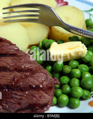 Gegrilltes Rumpsteak, Erbsen mit einem Stück Butter, gekochte Kartoffeln mit einer Gabel. Stockfoto