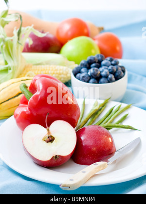 Nahaufnahme von geschnittenen Äpfeln und Paprika in Plage mit frischem Obst und Gemüse im Hintergrund Stockfoto