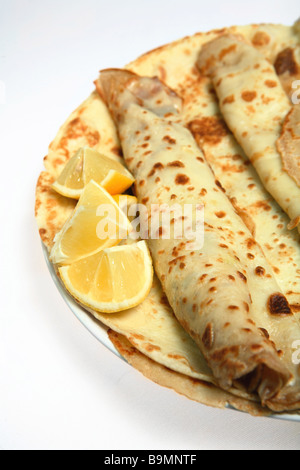 Ein Haufen von englischen Pfannkuchen (auch genannt Crepes) auf einer Platte mit Zitronenscheiben. Stockfoto