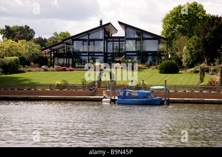 Blaues Boot ankern neben ein prächtiges Haus am Flussufer zwischen Hampton Court und Richmond Stockfoto