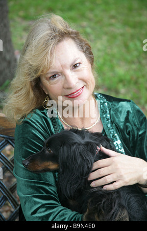 Eine Reife blonde Frau und ihr Liebling Langhaar Dackel entspannend im park Stockfoto