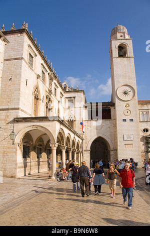 Touristen und Besucher flanieren außerhalb der Sponza-Palast und der Glockenturm in der ummauerten Stadt von Dubrovnik im Sommersonnenschein Dalmatien Stockfoto